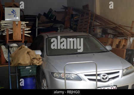 Hoarders garage auto, circondata da legno casuale e altri oggetti Foto Stock