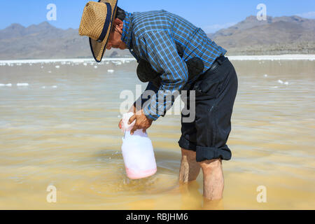 L'uomo in acque poco profonde di Salt Lake Urmia è il prelievo di sale dal pavimento del lago, West Azerbaijan provincia, Iran Foto Stock