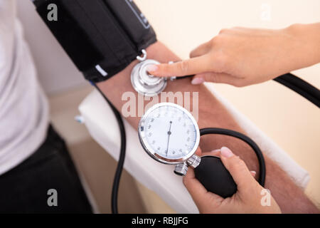 Close-up medico di misurare la pressione del sangue del paziente di sesso maschile Foto Stock