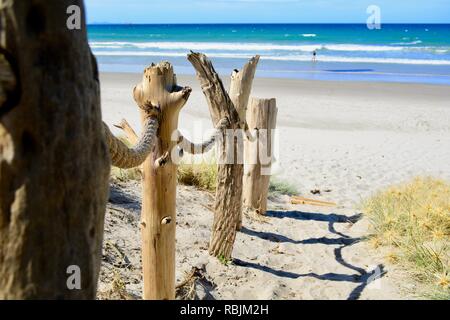 Una spiaggia sabbiosa ripido sentiero che conduce al mare; le decorazioni in legno su un lato del percorso; la bella giornata di sole e luminoso blu del mare invitano a fare una nuotata Foto Stock