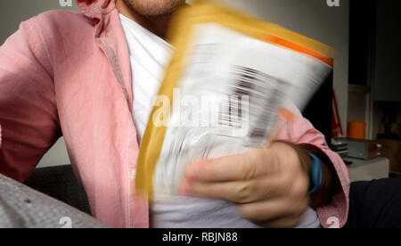 Parigi, Francia - Jan 10, 2018: uomo unboxing di Pitney Bowes pacchetto giallo con merci acquistate online da EBay Foto Stock