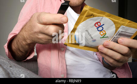 Parigi, Francia - Jan 10, 2018: uomo unboxing di aprire con taglierina Pitney Bowes pacchetto giallo con merci acquistate online da EBay Foto Stock