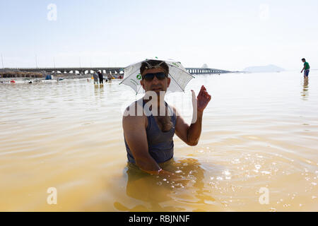 Un uomo che indossa e occhiali da sole a ombrello hat nel lago di Urmia, West Azerbaijan provincia, Iran Foto Stock