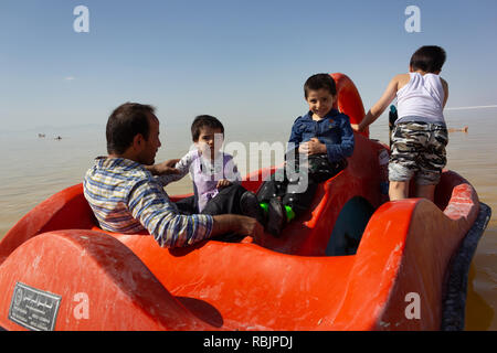 Un uomo è in sella a una barca a pedali con i suoi figli sul lago di Urmia, West Azerbaijan provincia, Iran Foto Stock