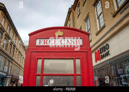 Il vecchio telefono rosso box ora utilizzato come un bancomat a Bath, Inghilterra, Regno Unito Foto Stock