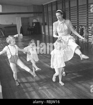 Ginnastica in 1940s. Un insegnante di donne nella palestra della scuola è che mostra come spostare e danza. Tre bambini in età diverse cerca di seguire il suo piombo. Foto Kristoffersson Ref AC3-1. La Svezia 1940s Foto Stock