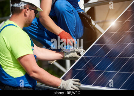 Due tecnici professionisti di collegamento foto solare pannello voltaico alla piattaforma di metallo usando un cacciavite. Stand-alone pannello solare Installazione sistema, ef Foto Stock