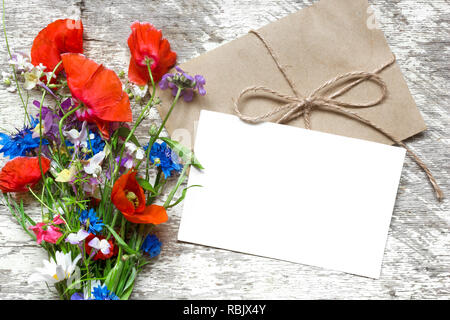 Branding elegante mockup per visualizzare le tue opere. bigliettino vuoto o invito a nozze con fiori di campo estivo su sfondo di legno. laici piatta Foto Stock