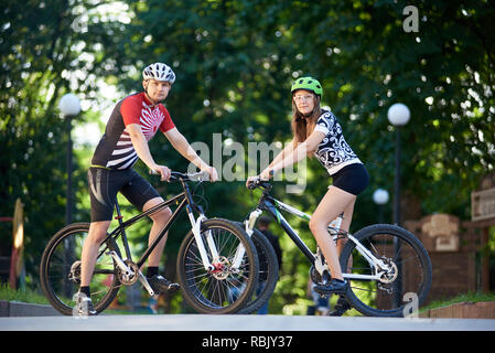 Coppia di ciclisti in abbigliamento ciclismo fermato a posare per foto. Donna e uomo che guarda alla telecamera, seduto sulla bici. L uomo e la donna la formazione insieme. Concetto di stile di vita sano Foto Stock