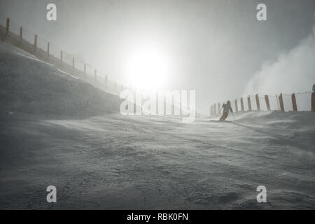 Uno sciatore che scende dalla cima della montagna in Les Arcs, giù un mogul campo attraverso il vento e il cloud computing Foto Stock