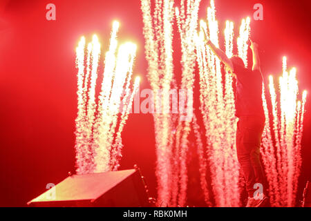 Superstar DJ martin garrix sorge sulla cabina del dj mentre i fuochi d'artificio è in background Foto Stock