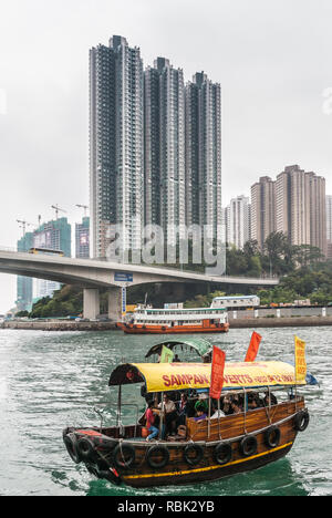 Hong Kong, Cina - 12 Maggio 2010: giallo con tetto di sampan viaggi nel vecchio porto centrale. Closeup shot. Cielo d'argento e acqua verdastra. Tall highrise b Foto Stock