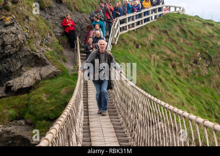 I turisti ed i visitatori possono esplorare e attraversare a piedi il ponte di corde a Carrick-a-Rede e Larrybane Bay sulla costa occidentale dell'Irlanda. Foto Stock