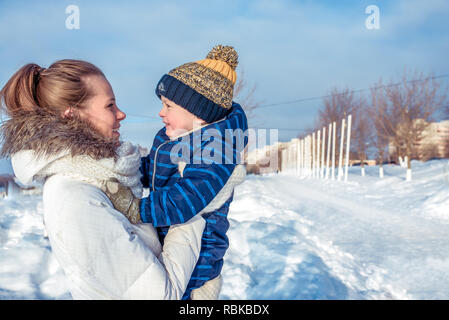 La mamma con il piccolo figlio di 3 anni, nella giornata di sole in una città in inverno. Spazio libero per il testo. Sorridenti relax nella natura. La famiglia felice in aria fresca. Foto Stock