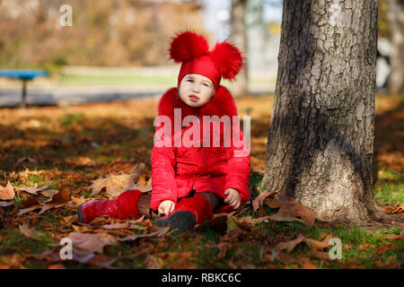 Dolly pin-up toothsome bambina indossa blushful rosso giacca invernale e caldo hat con stivali di moda abiti eleganti che pongono in autunno il parco di primavera settimana Foto Stock