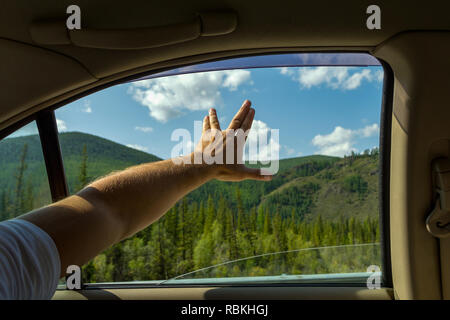 L'uomo di braccio, coperta di pelo, è aperto e mostra il segno di startrek dalle dita diffondere uno sfondo di cielo blu con nuvole bianche e verdi con Foto Stock