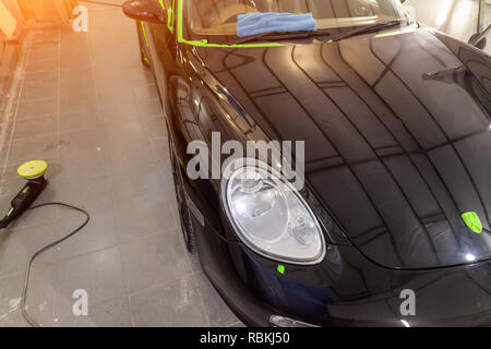 Per la cura e la manutenzione di un nero auto alla stazione dopo il lavaggio, coperto con cera, nascondendo i graffi, il corpo del veicolo utilizzando la lucidatura e grin Foto Stock