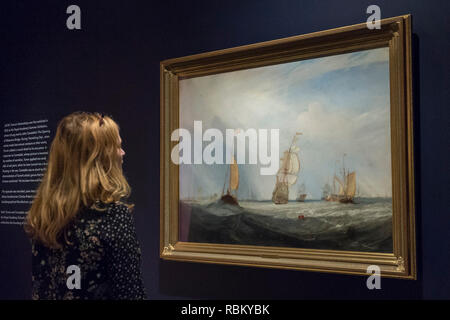 Londra, Regno Unito. 11 gennaio 2019. Un membro del personale opinioni 'Helvoetsluys', 1832, da J.M.W. Turner. La pittura viene mostrato con 'l'apertura di Waterloo Bridge ("Whitehall scale, Giugno 18th, 1817')" di John Constable presso la Royal Academy of Arts di Piccadilly per la prima volta poiché gli artisti si sono scontrati presso il salone estivo nel 1832. Le due opere la forma "Egli è stato qui e ha sparato una pistola": Turner, Constable e la Royal Academy, sul display dal 12 gennaio al 31 marzo 2019. Credito: Stephen Chung / Alamy Live News Foto Stock