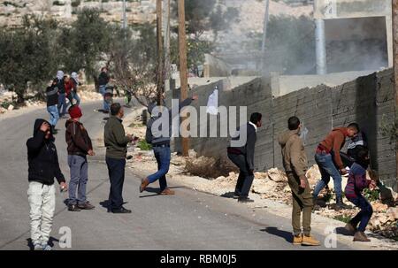 Nablus, West Bank, Territorio palestinese. Xi gen, 2019. I dimostranti palestinesi scagliare pietre verso le forze israeliane durante scontri a seguito di una dimostrazione settimanale contro l'espropriazione delle terre palestinesi da parte di Israele nel villaggio di Kfar Qaddum, vicino la Cisgiordania città di Nablus on gennaio 11, 2019 Credit: Shadi Jarar'Ah/immagini APA/ZUMA filo/Alamy Live News Foto Stock