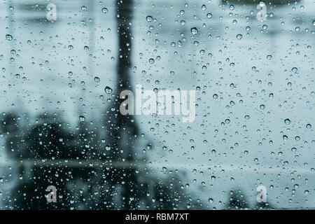 Gocce di pioggia sulla finestra; pavimento bagnato con la riflessione di un albero in background; profondità di campo