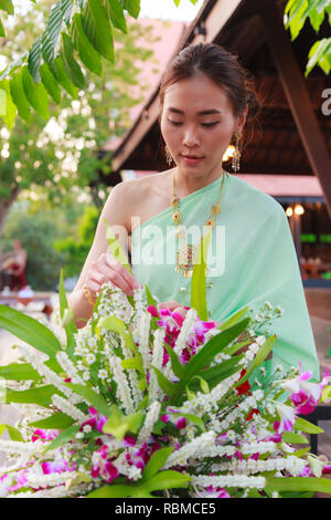 Giovani Thai bella donna asiatica medicazione vintage retrò tailandese tradizionale costume disponendo vaso di fiori. Thailandia culturali e tradizionali del turismo, Foto Stock