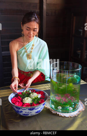 Giovani Thai bella donna asiatica medicazione vintage retrò tailandese tradizionale costume disponendo vaso di fiori. Thailandia culturali e tradizionali del turismo, Foto Stock