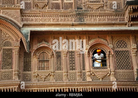 L'uomo fa capolino al di fuori della finestra del palazzo a Forte Mehrangarh, Jodhpur, Rajasthan, India, Asia Foto Stock