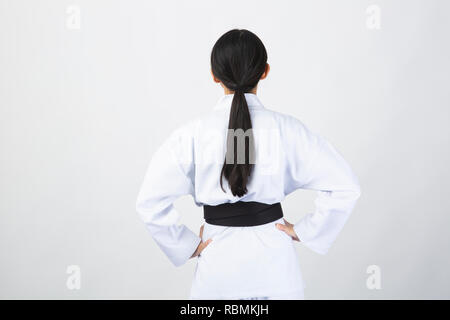 Giovane donna che indossa il karate suit tornando su sfondo bianco Foto Stock