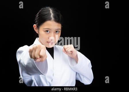 Giovane bella donna che indossa una tuta di karate karate esecuzione su sfondo nero Foto Stock