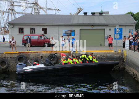 Persone che indossano giubbotti di salvataggio pronto ad adottare una rigida gonfiabile (nervatura) tour in barca dal molo Anseatica nel porto di Bergen, Norvegia. Foto Stock