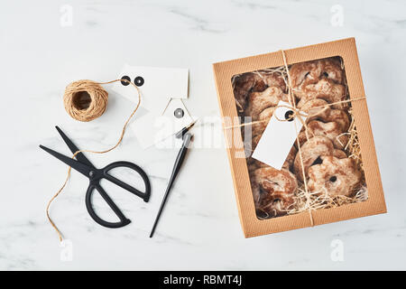 Natale fresco gingerbread cookie di glassa in carta marrone confezione regalo con vuoto tag regalo per il nome o il messaggio, la calligrafia pen, nastro e un paio di forbici o Foto Stock