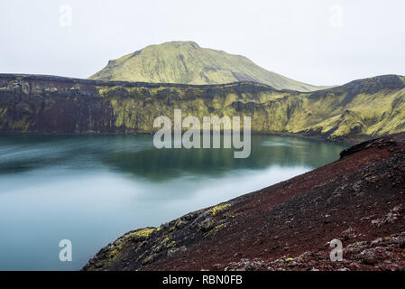 Silenzio al lago cratere islandese circondato da rocce colorate Foto Stock