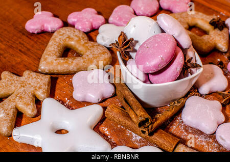 Bianco e rosa gingerbreads Natale in una ciotola con una stella di anice e cannella bastoni su una cucina in legno counter Foto Stock