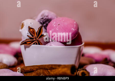 Bianco e rosa gingerbreads Natale in una ciotola con una stella di anice e cannella bastoni su una cucina in legno counter Foto Stock