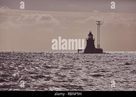 Silhouette di un faro all'orizzonte al tramonto, il fuoco selettivo, tonificazione del colore applicato. Foto Stock