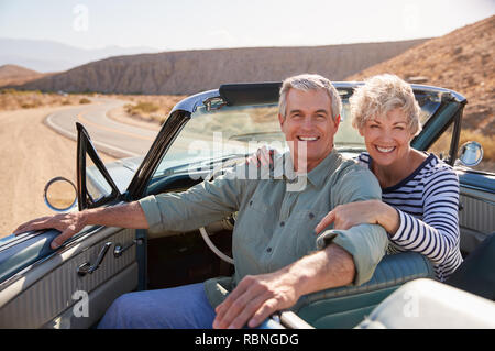 Coppia senior sorriso per telecamera da open top car, close up Foto Stock