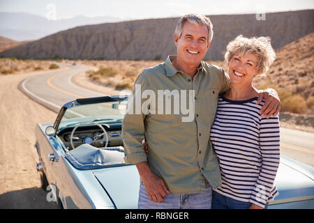 Coppia senior sul viaggio in piedi in auto sorridente alla fotocamera Foto Stock