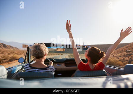 La mamma la guida auto, figlia con le mani in aria, vista posteriore Foto Stock