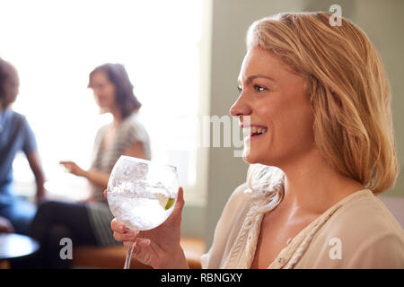 Close up della giovane donna tenendo un drink in un pub, vista laterale Foto Stock