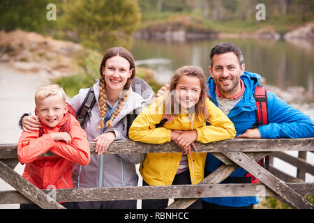 Famiglia giovane appoggiato su di una recinzione di legno in campagna, guardando la telecamera, close up Foto Stock