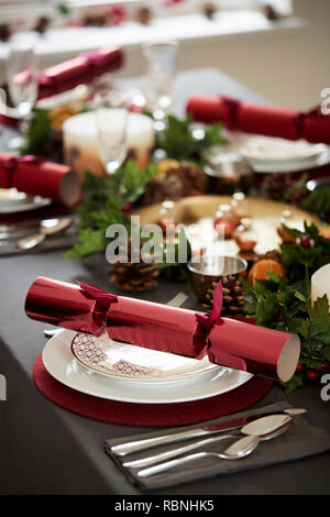 Close up di Natale decorati impostazione tabella, con fulcro ed Christmas Cracker disposte su piastre Foto Stock