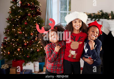 Ritratto di bambini indossare i ponticelli di festosa e cappelli per celebrare il Natale a casa insieme Foto Stock