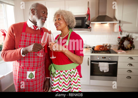 Senior coppia nero indossando grembiuli prendere una pausa dal preparare la cena di Natale per fare un brindisi, close up Foto Stock