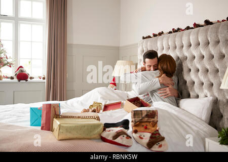 Giovane costeggiata nel letto di casa come lo scambio di doni il giorno di Natale Foto Stock