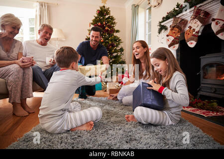 Tre generazioni la famiglia indossando pigiami nel salotto di casa doni di apertura il giorno di Natale Foto Stock