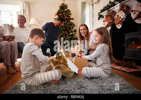 Tre generazioni la famiglia indossando pigiami nel salotto di casa doni di apertura il giorno di Natale Foto Stock