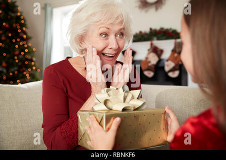 Nonna eccitato ricevere regali di Natale dal nipote a casa Foto Stock