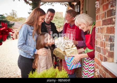 Famiglia essendo accolti dai nonni che arrivano per visitare il giorno di Natale con doni Foto Stock