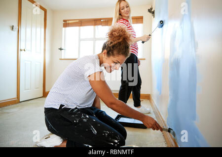 Due donne Decorazione di stanza in casa nuova parete di verniciatura Foto Stock