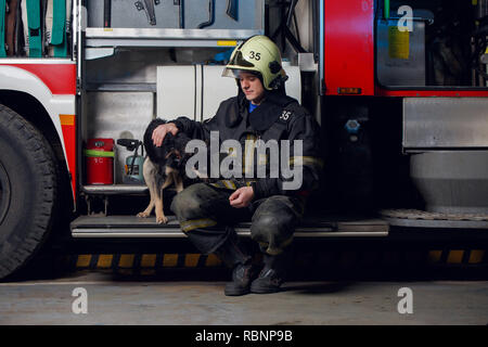 Foto di vigile del fuoco nel casco con il cane Foto Stock